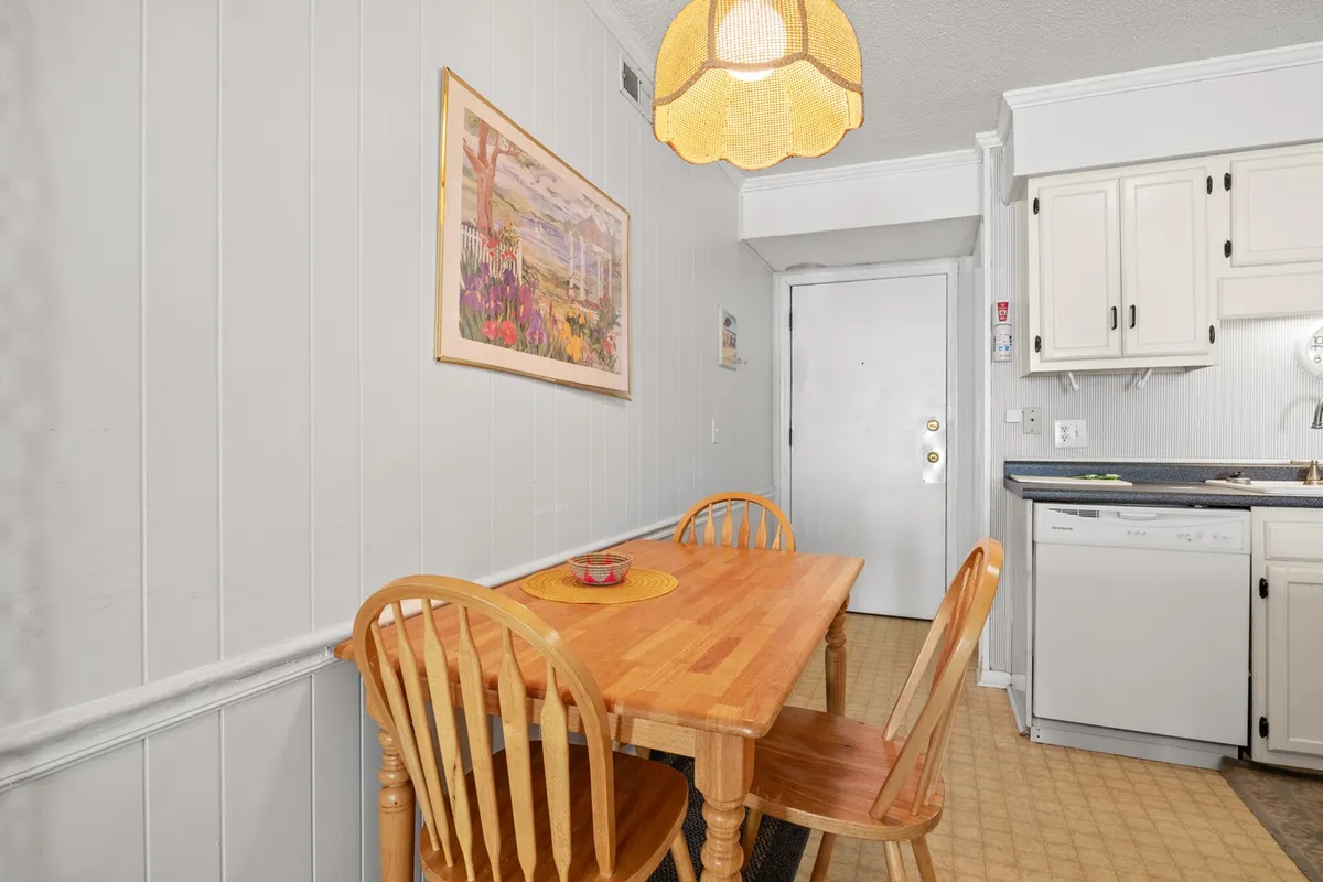 A welcoming dining area with a wooden dining table and four chairs, complemented by framed artwork and visible kitchen appliances. The atmosphere is cozy and ideal for shared laughter and meals.